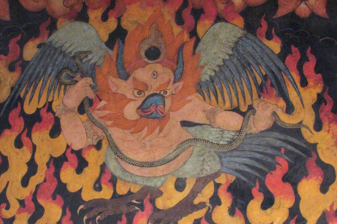 This Garuda, depicted above the empty halo of flames, shows evidence of having been painted in a later era than the rest of the temple's program of murals. Rather than a simple animated line, this region is painted in bright pigments, applied directly to the clay walls. A garuda in the flaming halo of a protector deity